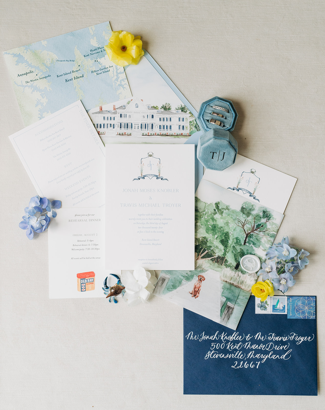 Custom invitation flatly for a coastal wedding on Kent Island, Maryland. Featuring a dark blue, hand calligraphed envelope, watercolor portraits of the venue and the couples dog on a dock, and the couples wedding rings.